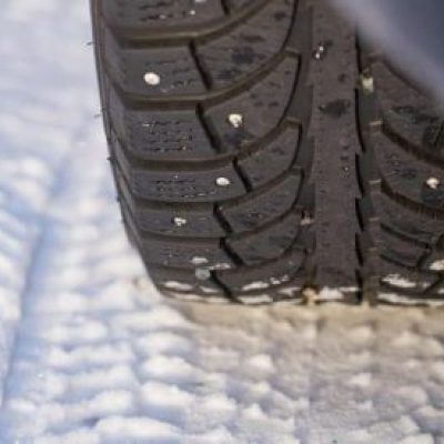 Winter wheel of the car with metal spikes. Copy space.